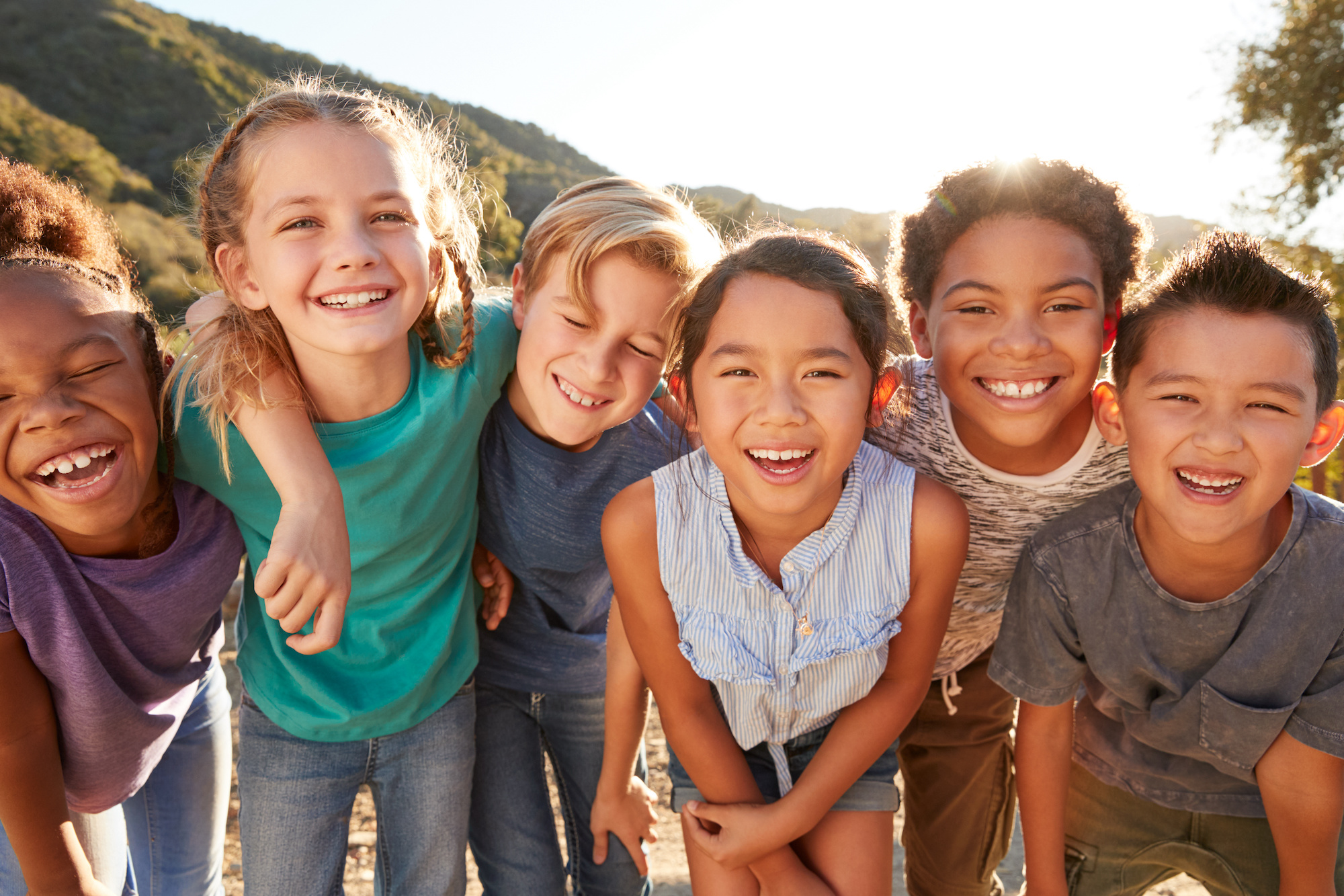 Group of smiling children showcasing confident smiles outdoors, emphasizing the social and personal benefits of orthodontic care at Noble Orthodontics in Chapel Hill.