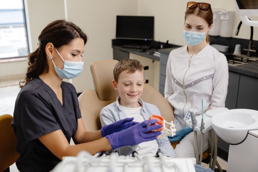Child engaging with orthodontist showing dental model in clinic, emphasizing airway health and orthodontic treatment benefits.